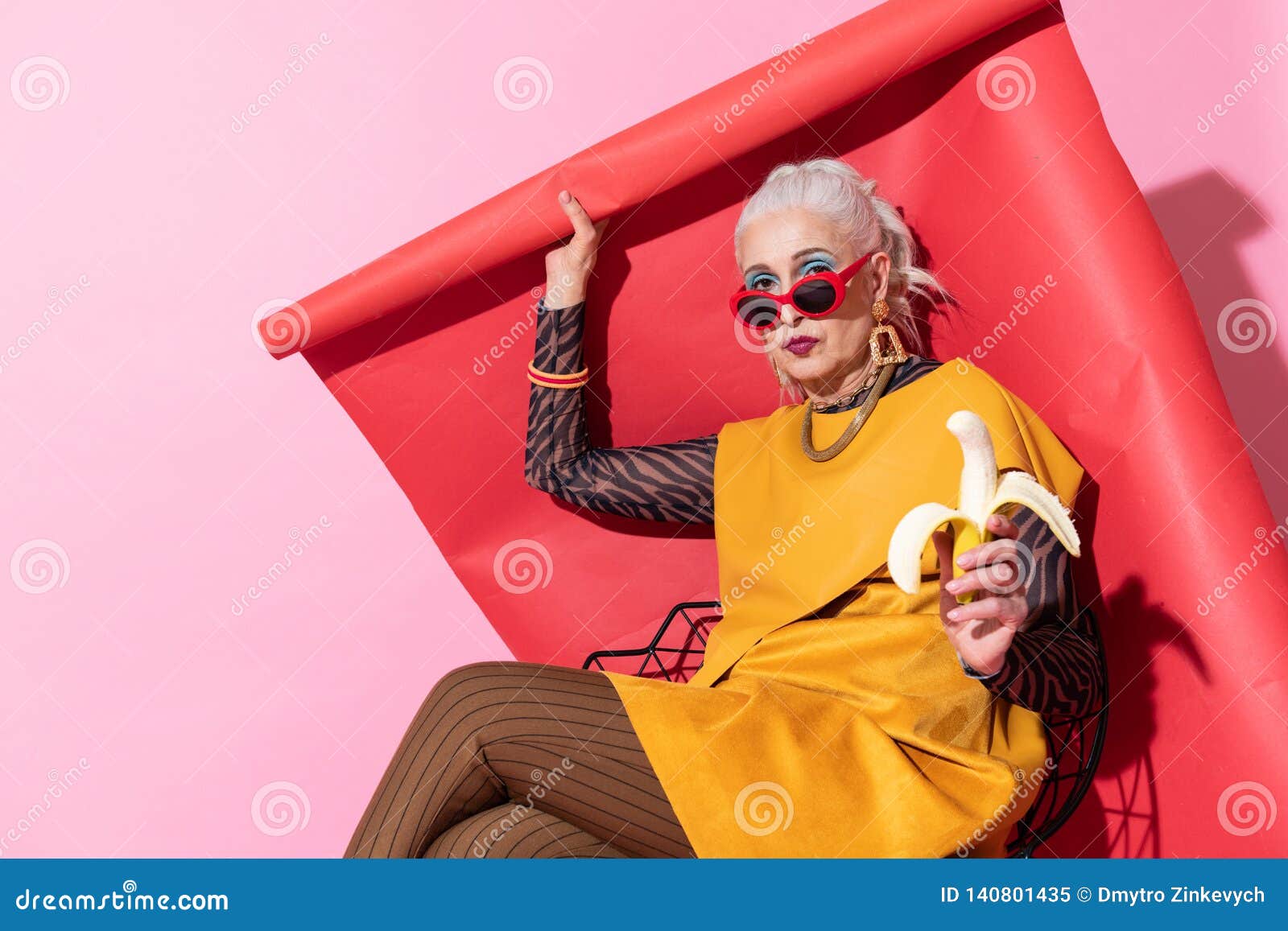 Persona femminile attenta che pensa al tempo di cena. Fondo rosso Donna bionda attraente che preme le labbra mentre esaminando macchina fotografica