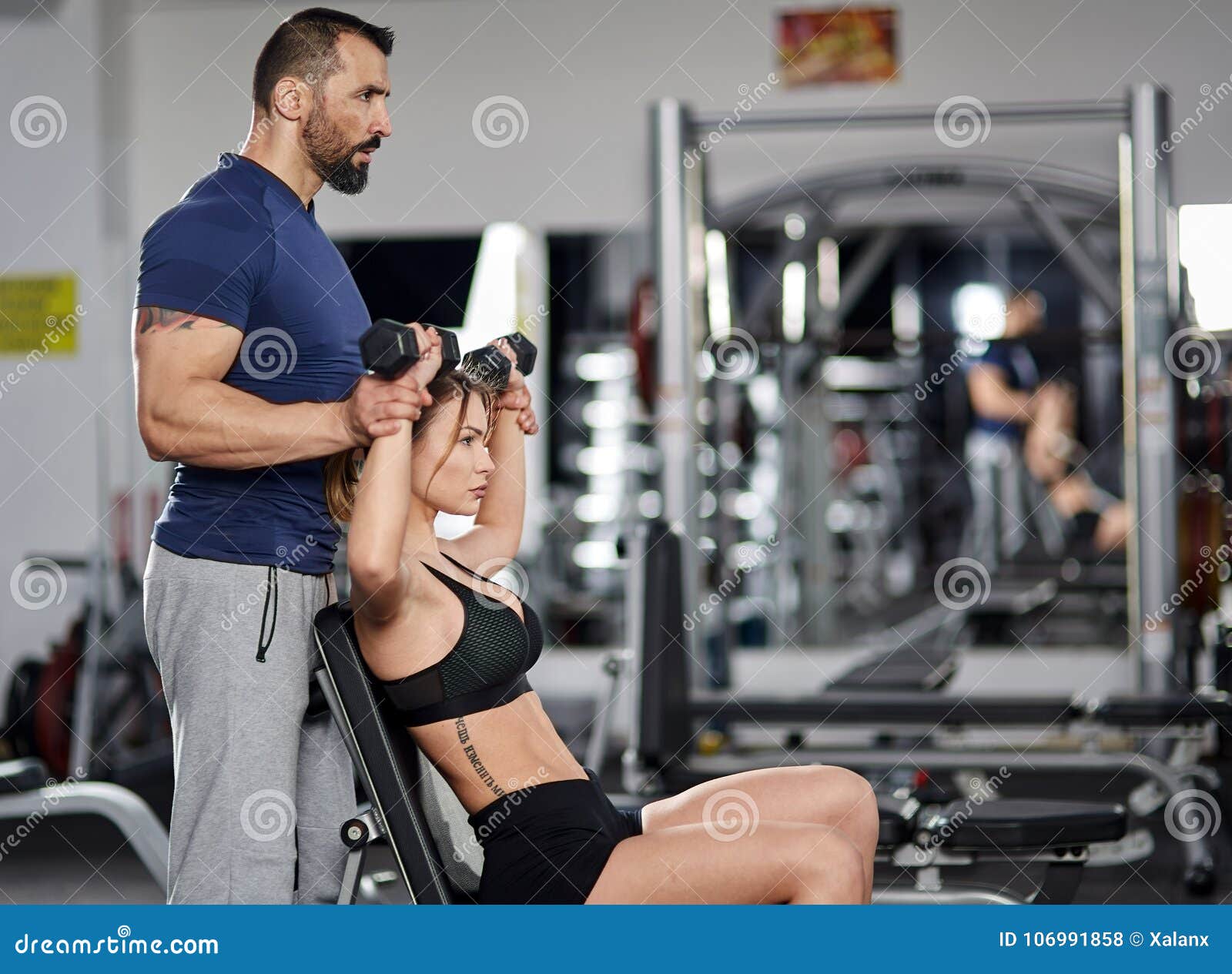 Personal Trainer Assisting Young Woman In The Gym Stock Photo Image Of Personal Lift