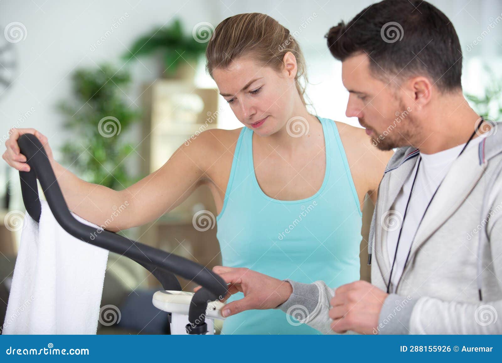 Personal Trainer Explaining How To Use Fitness Machine Stock Photo