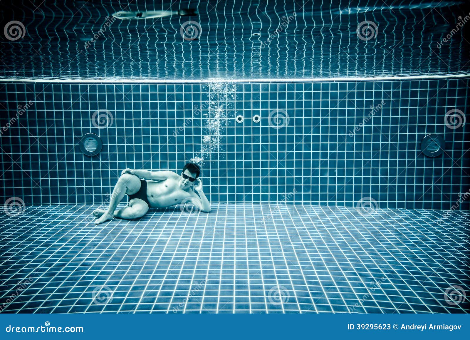 persons lies under water in a swimming pool