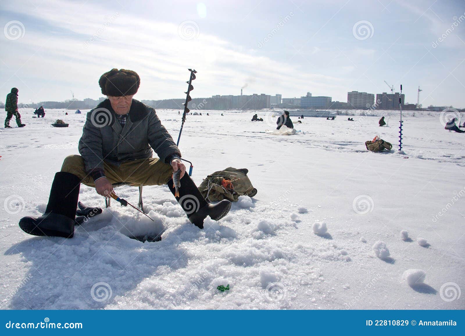 Los hombres engancharon a la pesca del invierno en el mar de Ob en Siberia. Un hombre agujerea el hielo, el otro pescado en los agujeros en el hielo. Los hombres rusos están muy encariñados con la pesca del hielo. Incluso si temperatura del aire is-30C. Pesca del invierno - es como la meditación y cómo ser sola, lejos de la esposa y de los colegas habladores. 26 de marzo de 2009 en la Novosibirsk, Rusia