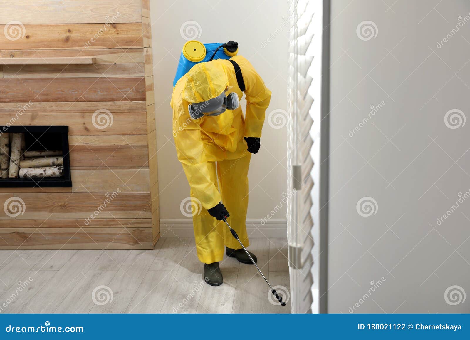 Pest Control Worker in Protective Suit Spraying Insecticide on Floor