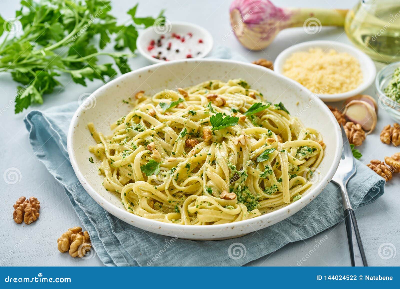 pesto pasta, bavette with walnuts, parsley, garlic, nuts, olive oil. side view, close-up, blue background.