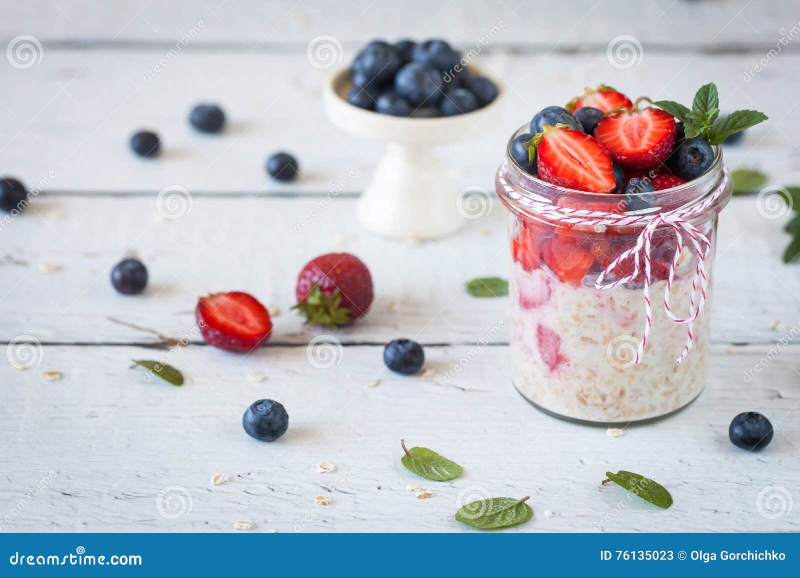 Petit déjeuner sain : avoine durant la nuit avec les fraises fraîches. Petit déjeuner sain : avoine durant la nuit avec les fraises et les myrtilles fraîches dans un pot en verre avec de la ficelle white&red, décorée de la menthe