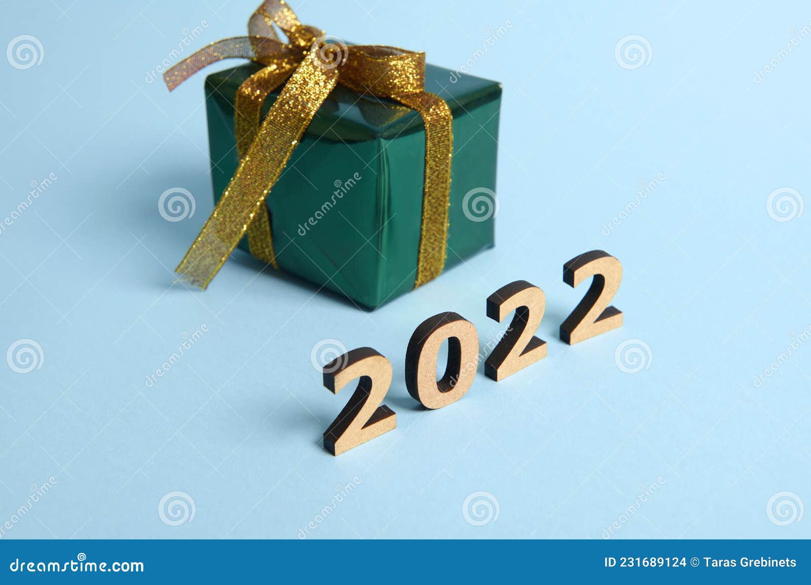 Petite Boîte Cadeau Enveloppé Dans Du Papier D'emballage Vert Brillant Et  Ruban or Et Arc Sur Fond Bleu Avec Des Numéros En Bois a Photo stock -  Image du brillant, noël: 231689124