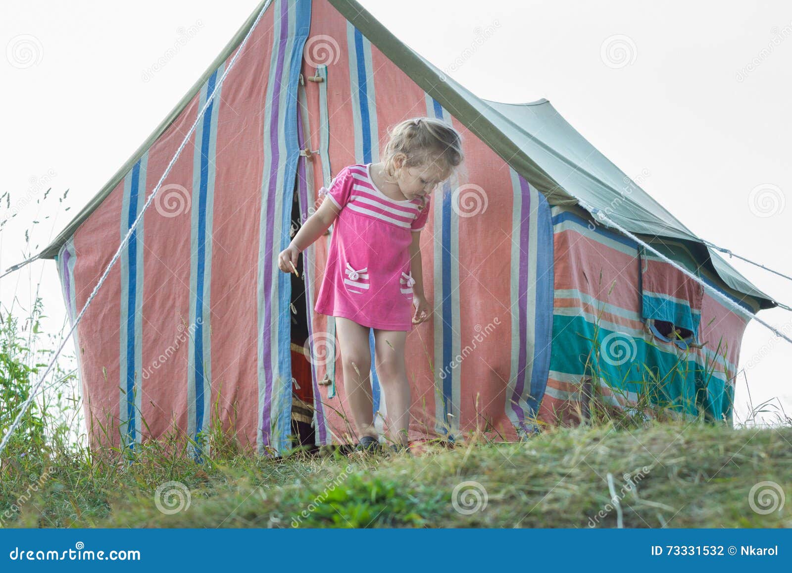 Petite Fille Se Tenant Près De La Tente De Toile Rayée De Camping