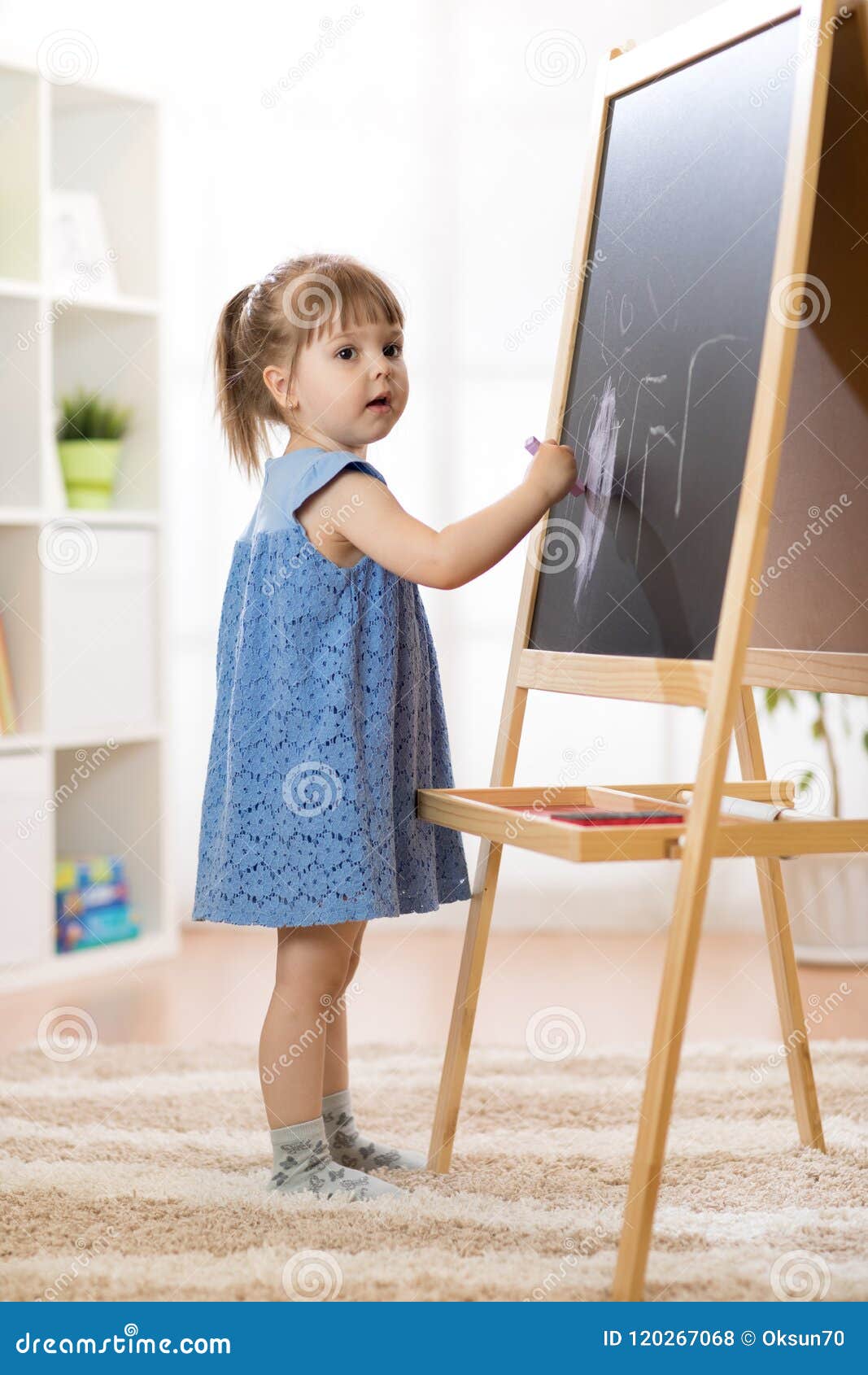 Peu De Fille D'enfant Dessine Avec La Craie Sur Le Tableau Noir