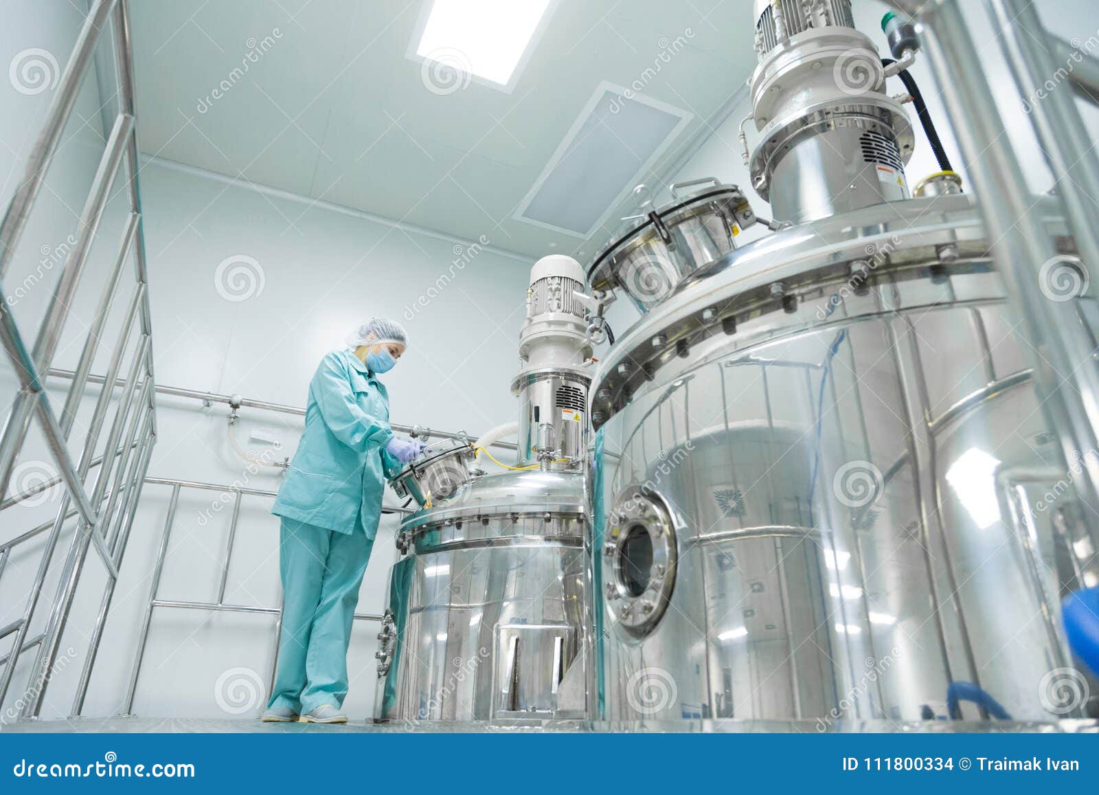 pharmaceutical factory woman worker in protective clothing operating production line in sterile environment