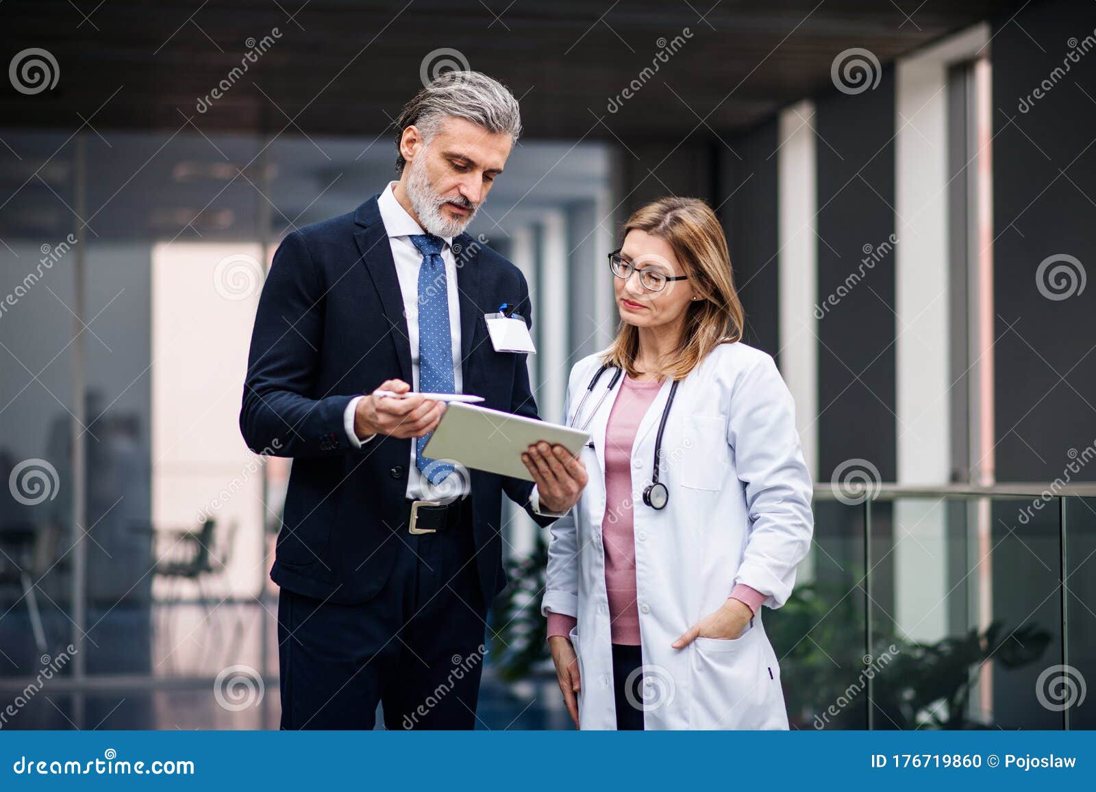 pharmaceutical sales representative with tablet talking to doctor.