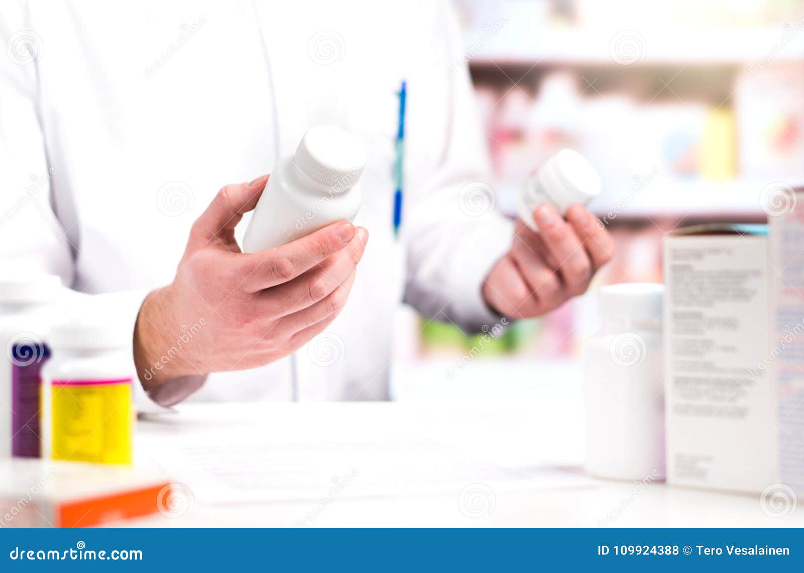 pharmacist in pharmacy. holding two bottles of pills.