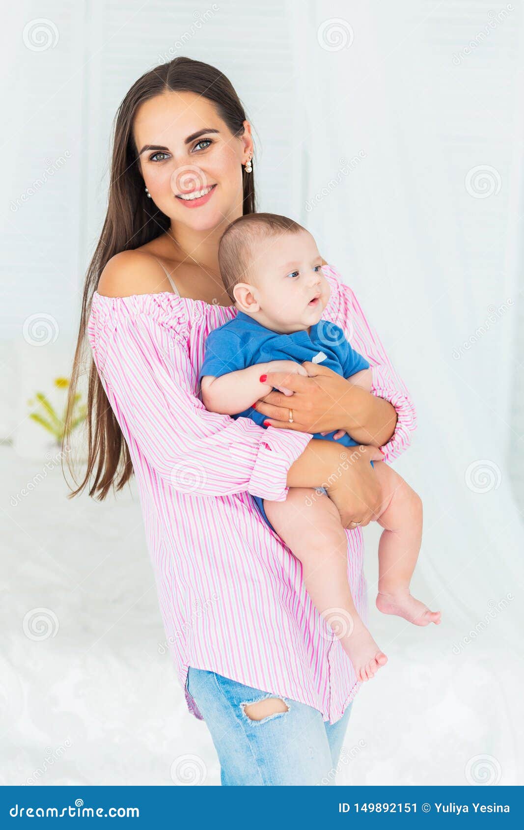Beautiful young mother holding her little baby son in her 