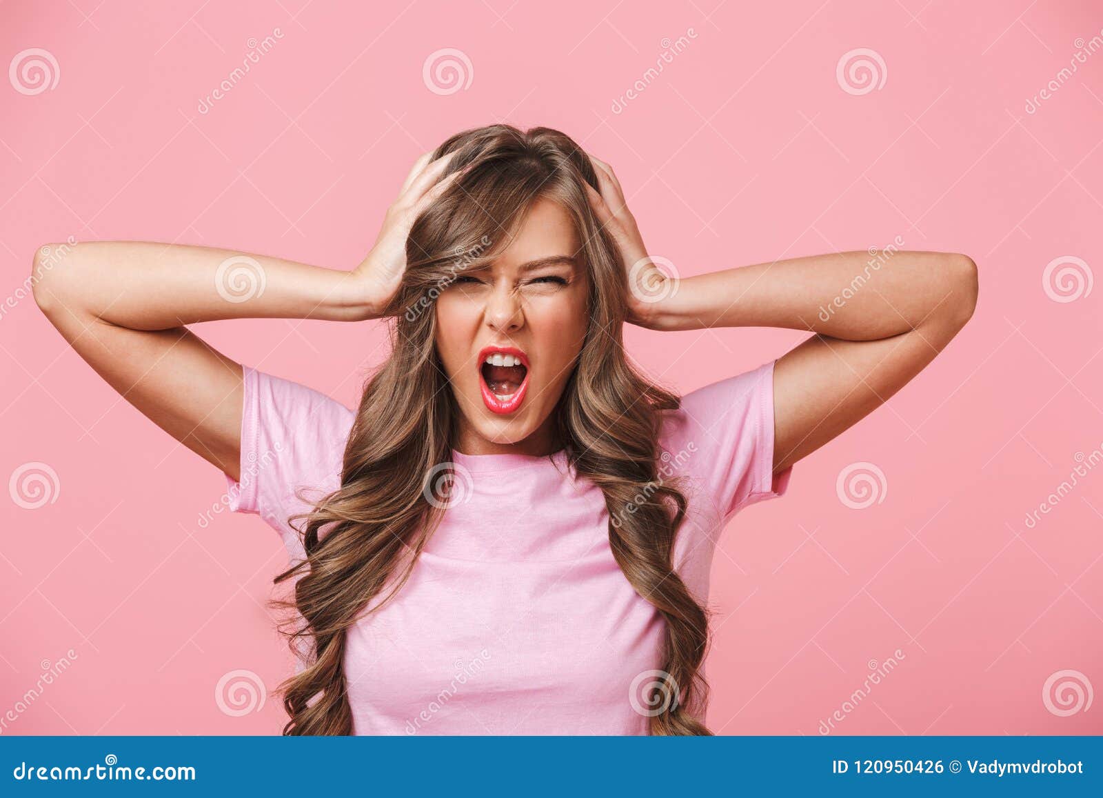 photo closeup of annoyed angry woman with long curly hair in basic t-shirt covering ears and screaming because of terrible