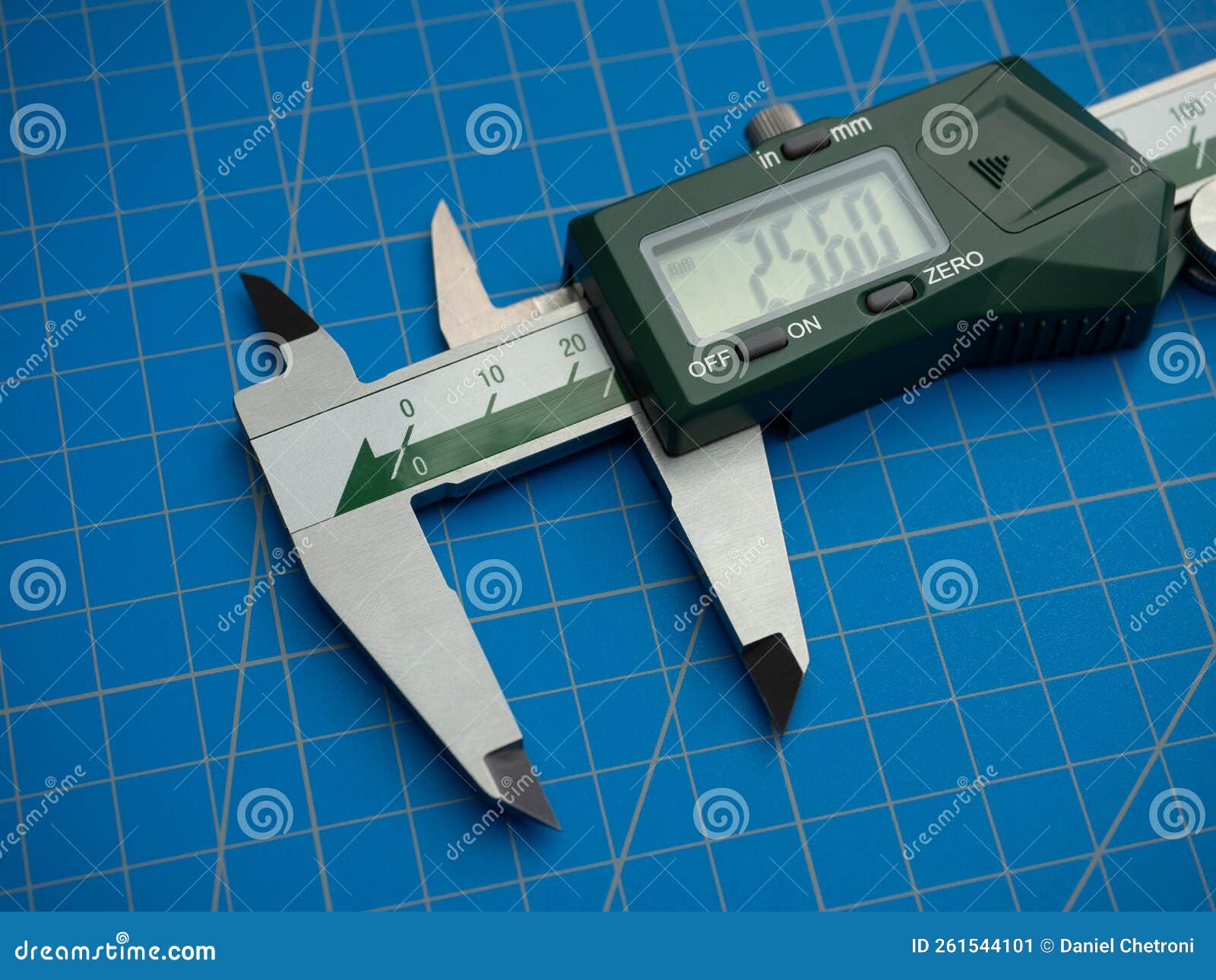 photo of a digital vernier caliper with centimeters and millimeters on a blue background cutting mat