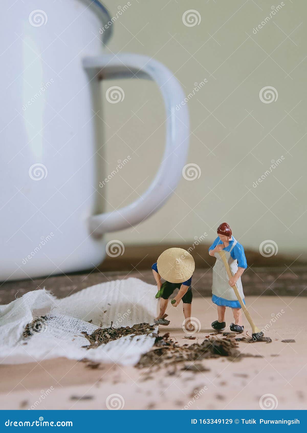 photo mini figure toy woman and farmer cleaning spilled tea at wooden board beyond small white aluminium glass