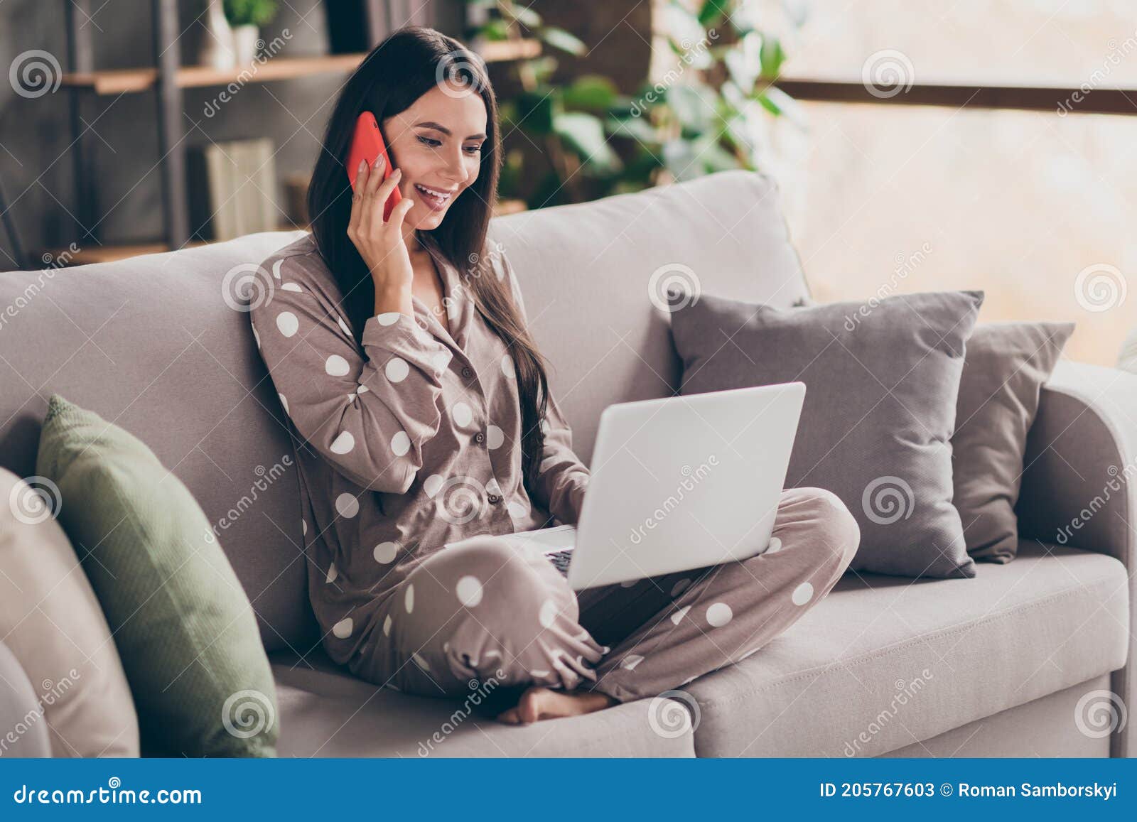 photo of nice optimistic girl sit write laptop talk telephone wear pijama at home