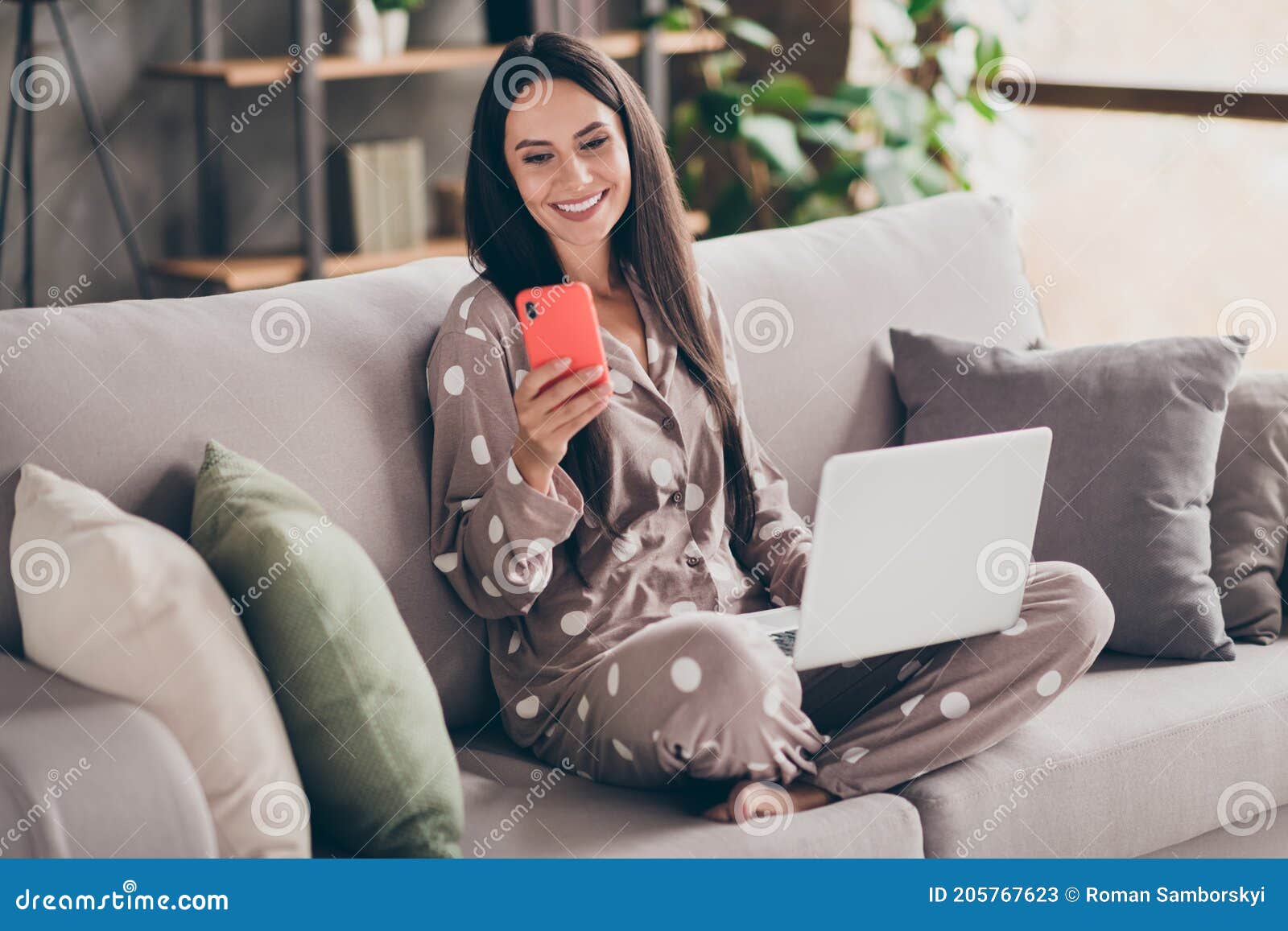 photo of nice optimistic girl sit write telephone hold laptop wear pijama at home