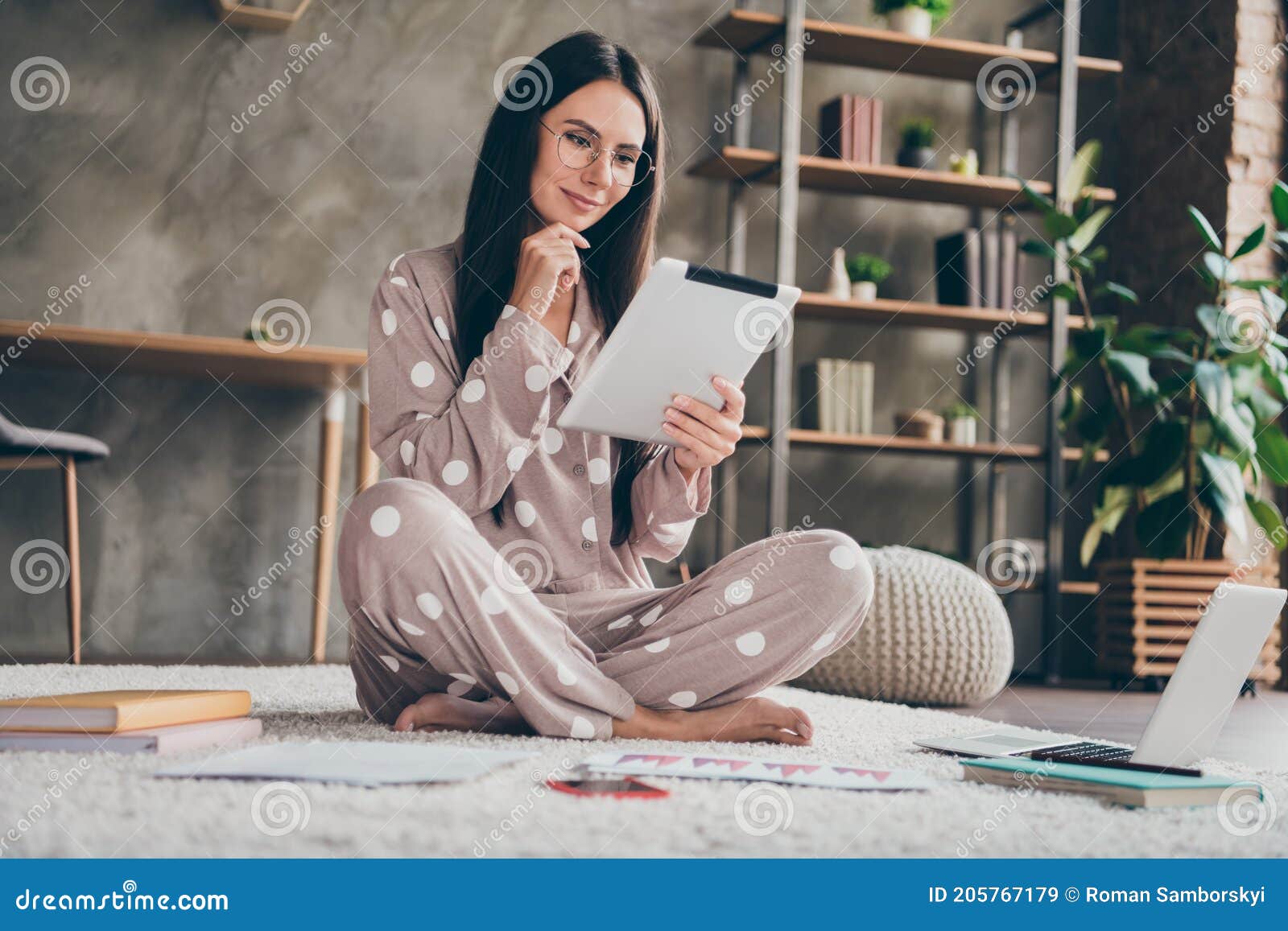 photo of nice sweet girl sit on carpet hand face type tablet wear spectacles pijama at home
