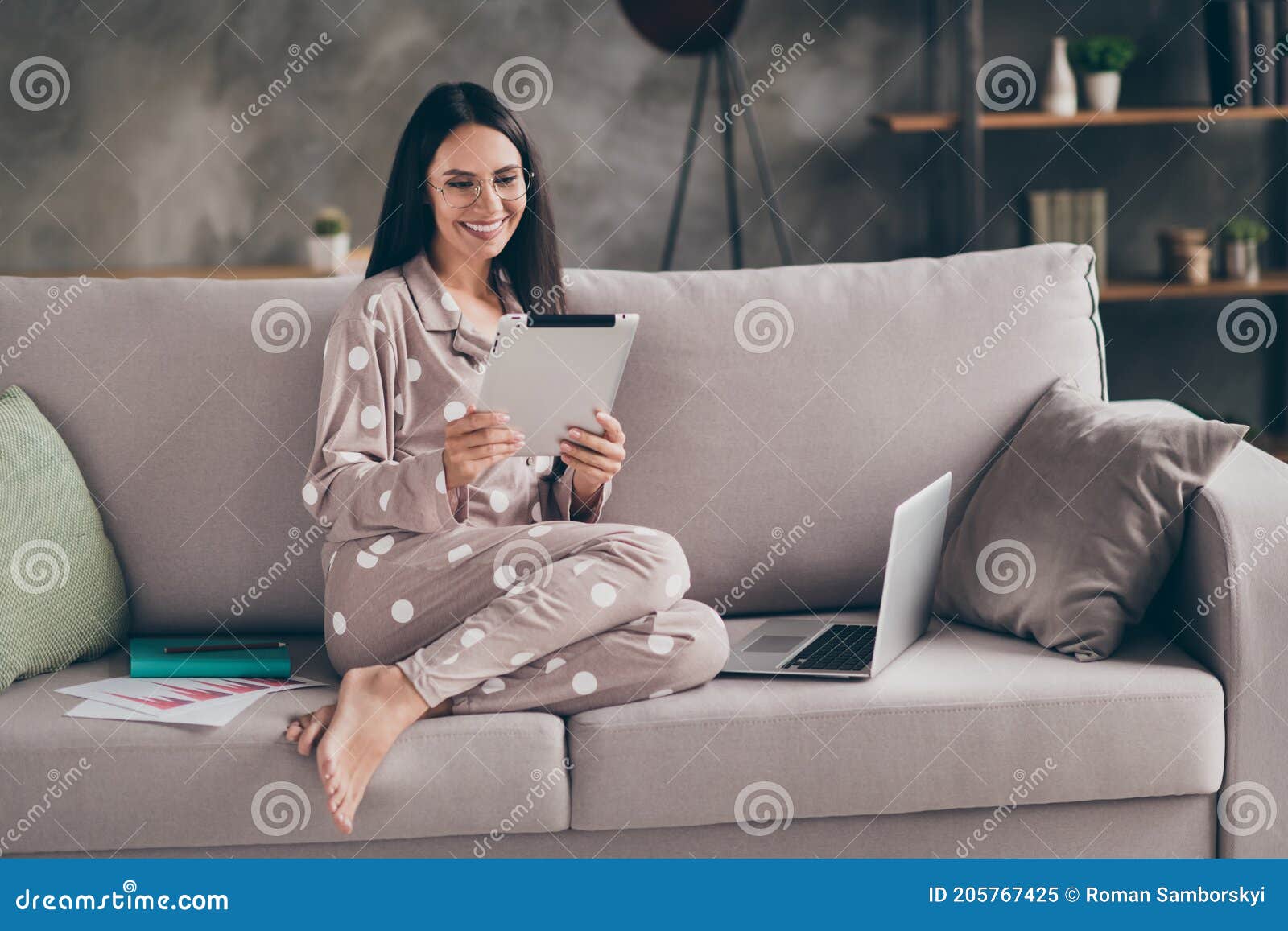 photo of pretty optimistic girl sit write tablet wear spectacles pijama at home on sofa