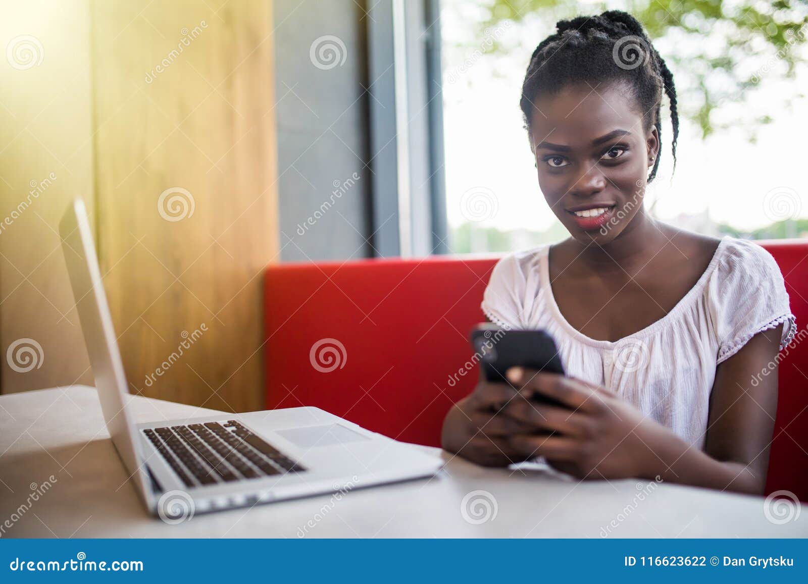 Smiling Beautiful Woman Using Mobile Phone while Sitting at Cafe. Young ...