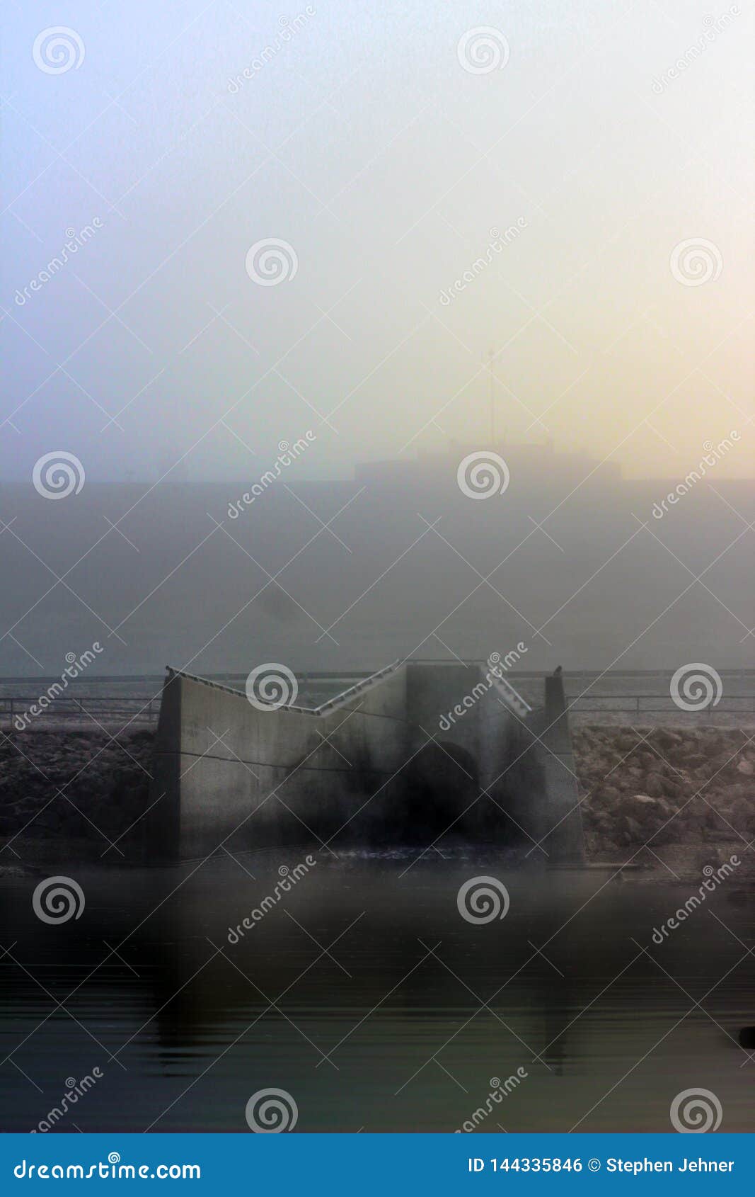 hazy morning view of a spillway from a large reservoir