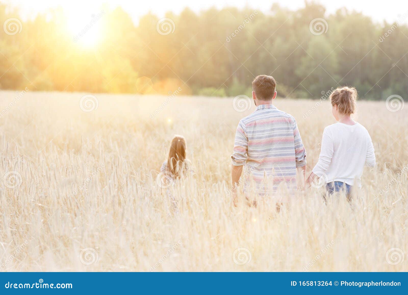 young caucasian family walking across field with young girl holding bouquet of flowers, concept organic ecologically friendly fami