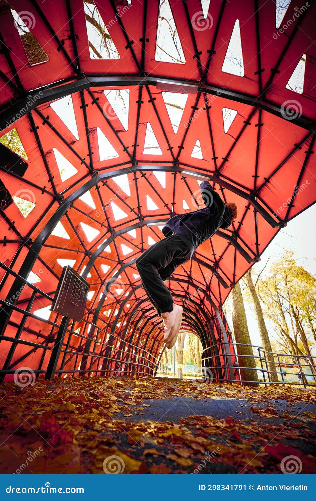 photo of young man, guy performing insane tricks, jumping and kicking action, circle looping wall in public park.