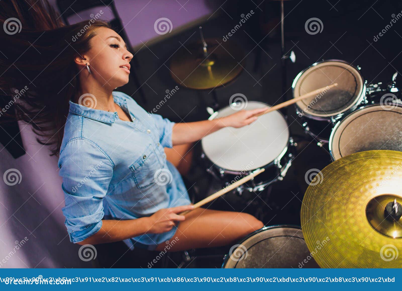 Photograph of a Female Drummer Playing a Drum Set on Stage. Stock Photo