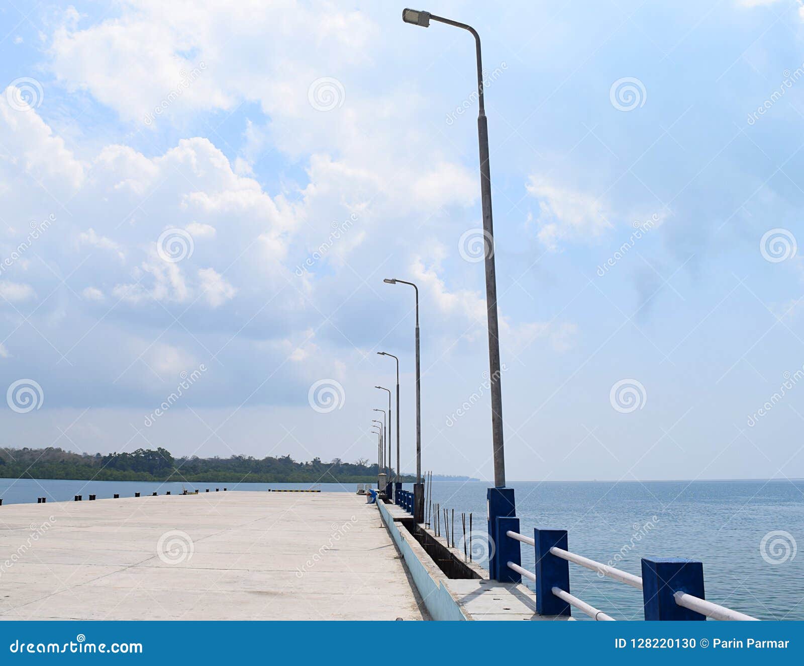 uncrowded ferry jetty with poles of light in open sea and cloudy sky