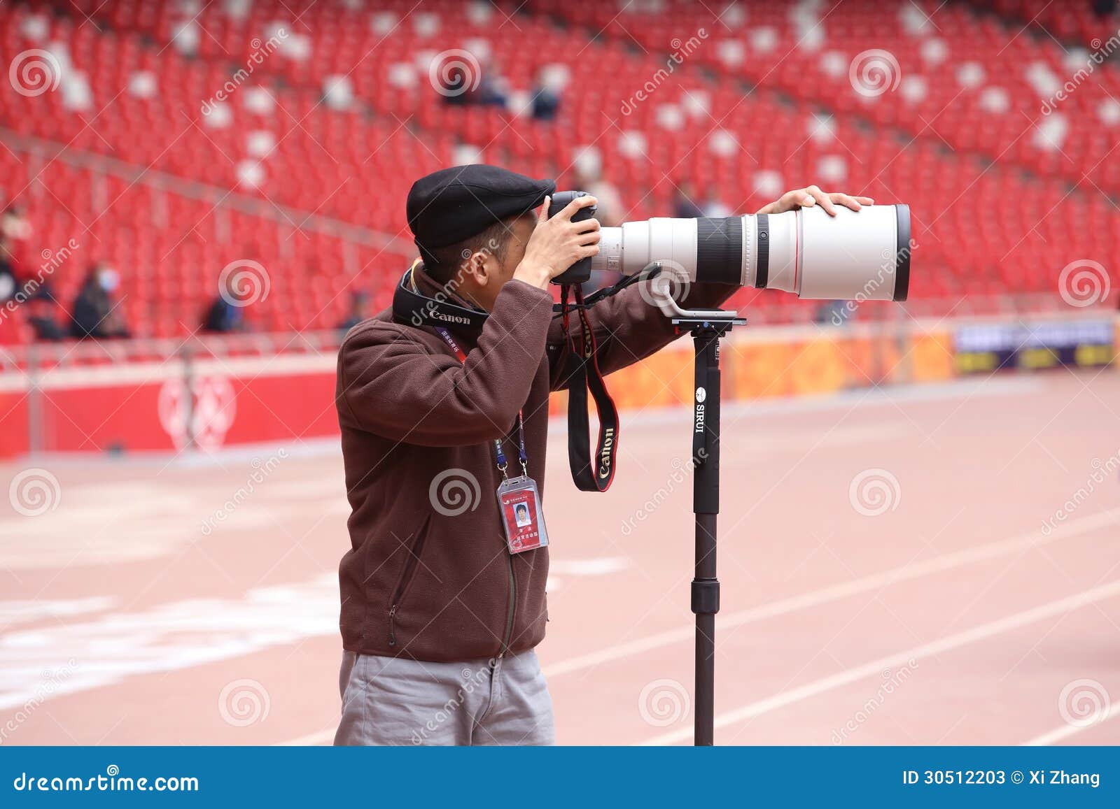 Photographer With Canon Lens. Photographer holds camera with telephoto lens in the stadium.