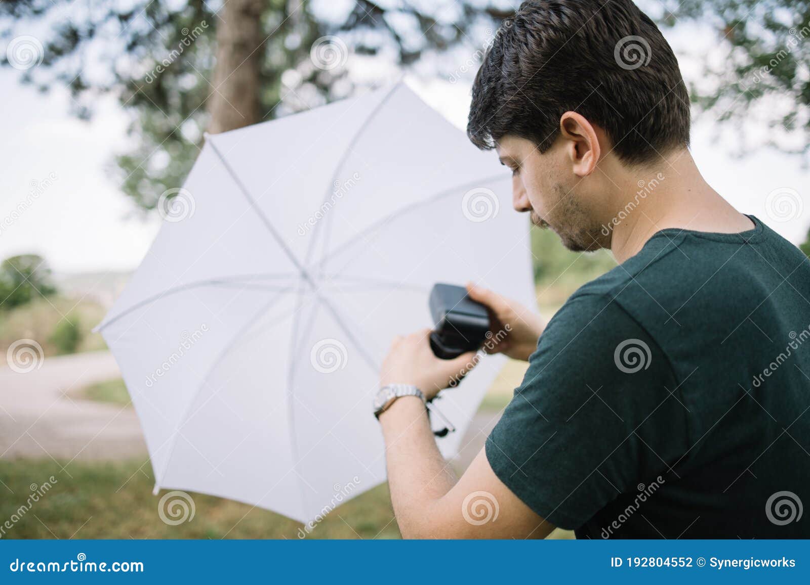Photographer Setting Flash Light on a Tripod with Umbrella Stock Photo