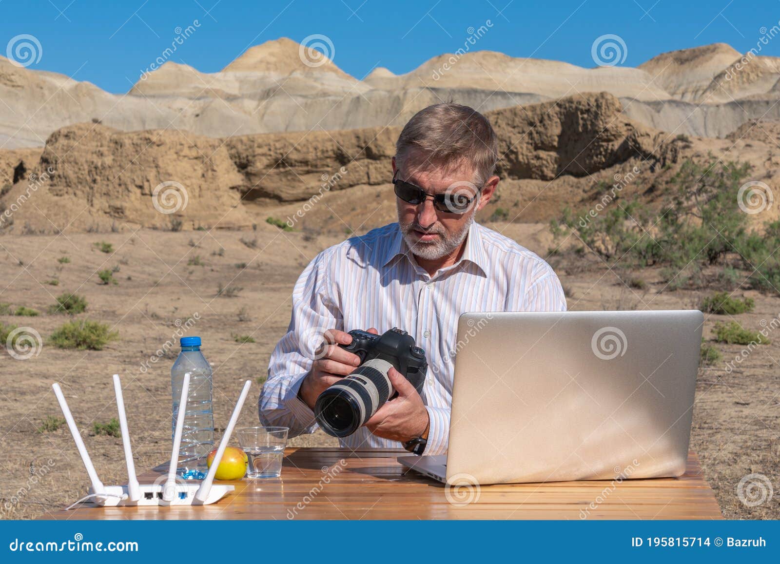 Photographer in Sunglasses Working at Table Outdoors on Laptop Stock