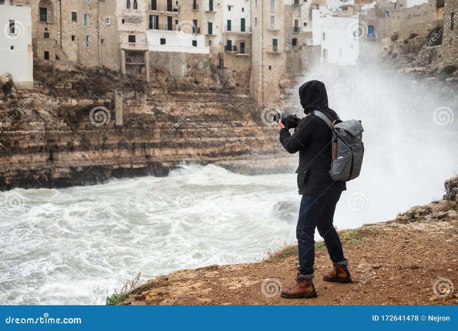 photographer taking picture of a stormy sea in polignano a mare, italy