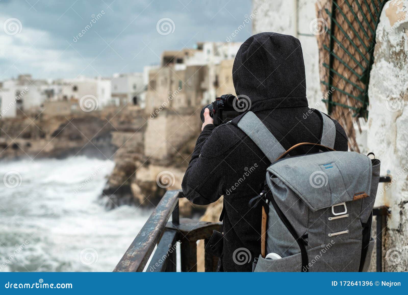 photographer taking picture of a stormy sea in polignano a mare, italy