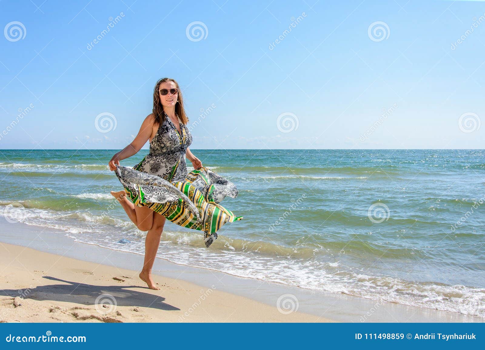 A Pretty Woman Running Along a Black Sea Beach in a Dress Up Against ...