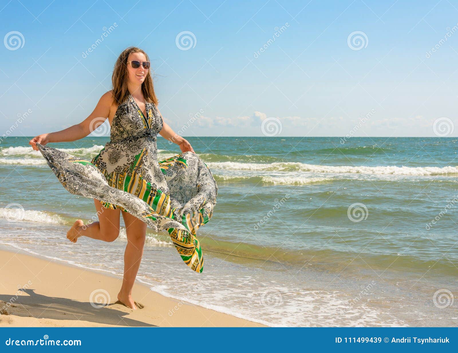 A Pretty Woman Running Along a Black Sea Beach in a Dress Up Against ...