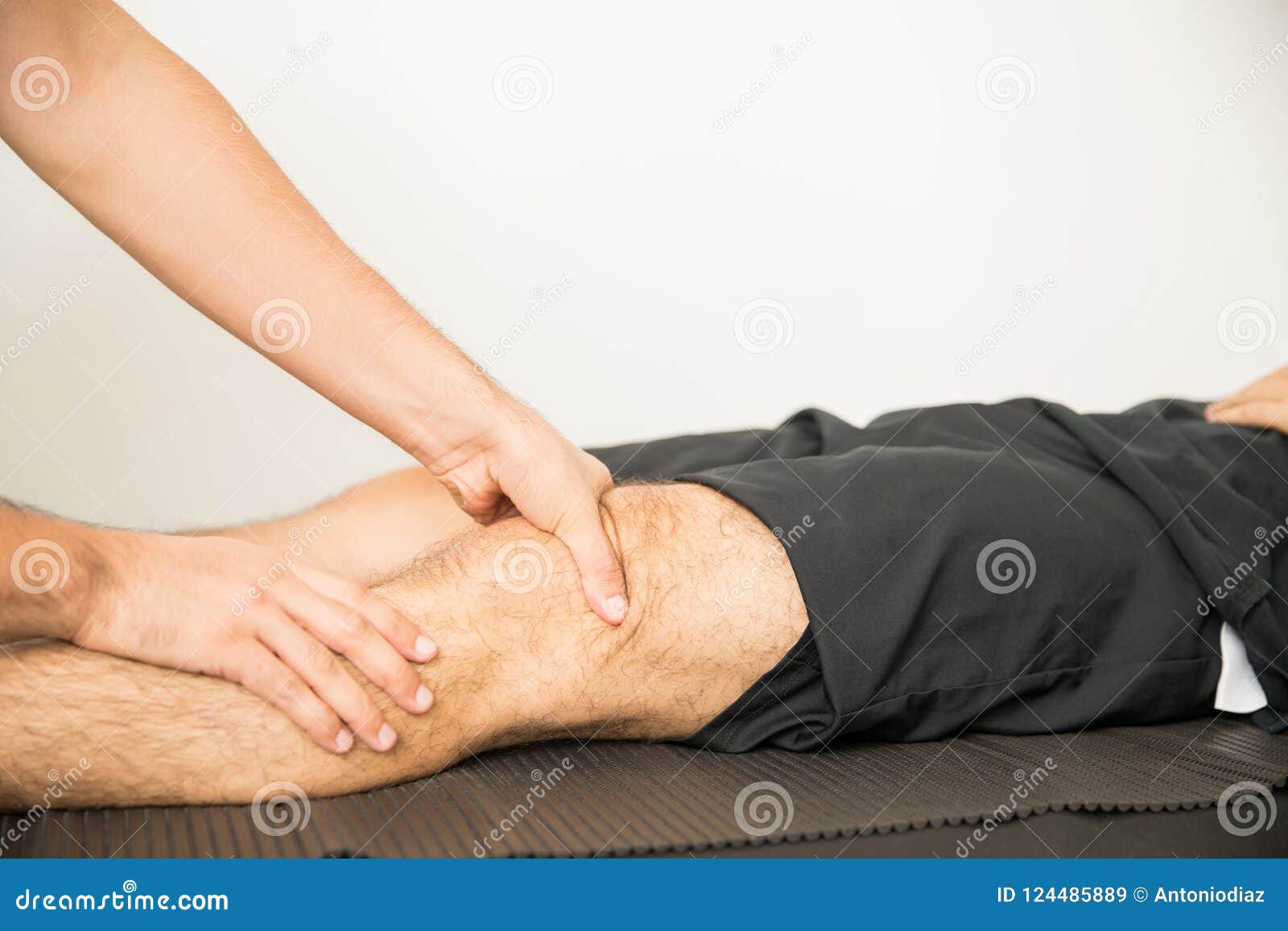 Physiotherapist Applying Pressure To Massage Young Mans Knee Stock