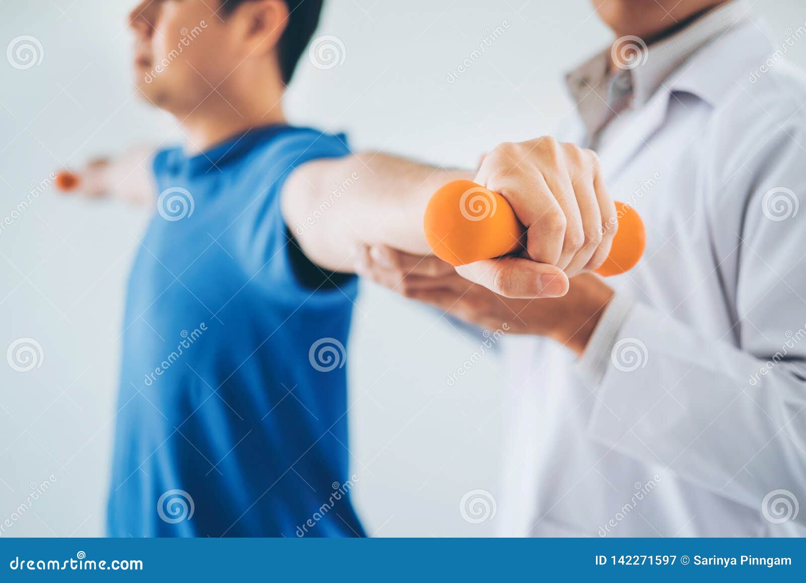 physiotherapist man giving exercise with dumbbell treatment about arm and shoulder of athlete male patient physical therapy