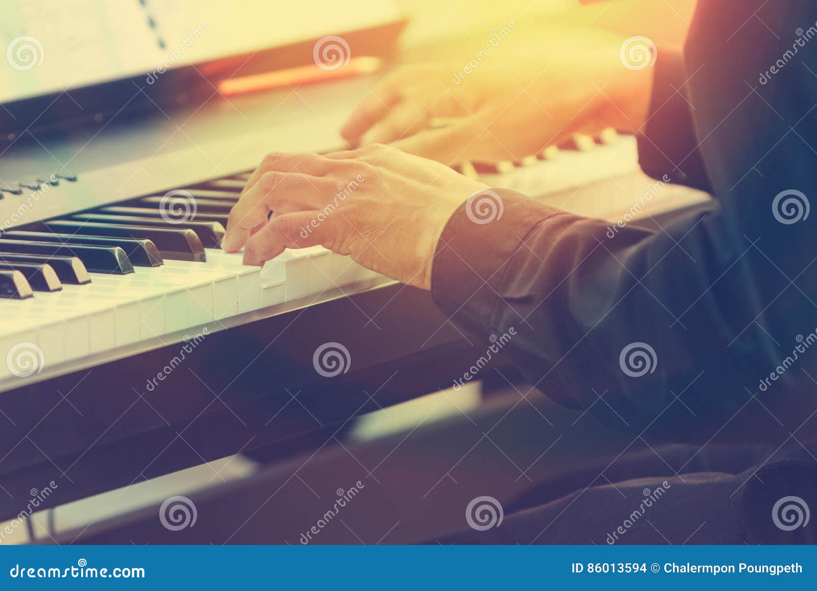 pianist hands playing piano in a outdoor concert with sun flare