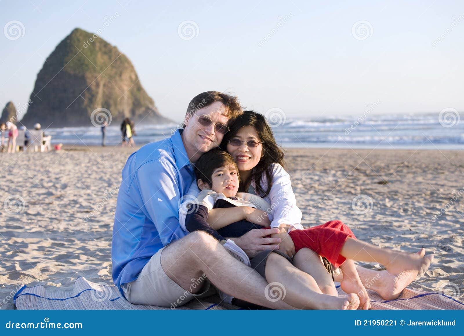 Piccola famiglia con il ragazzo invalido che si siede alla spiaggia. Piccola famiglia con il ragazzino invalido che si siede alla spiaggia dall'oceano