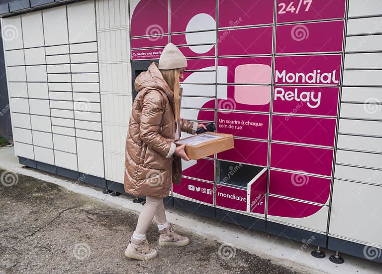Picking Up a Parcel from a Mondial Relay Locker by a Young Woman. Lockers Mondial Relay. Pickup