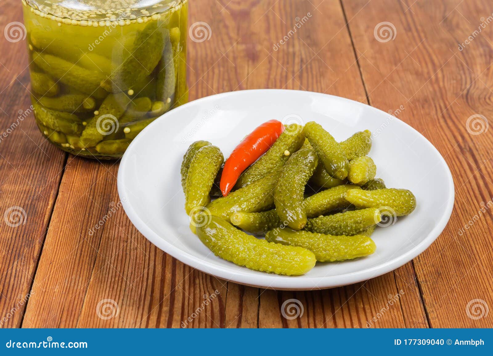 Pickled Gherkins on Saucer Against the Jar on Rustic Table Stock Photo