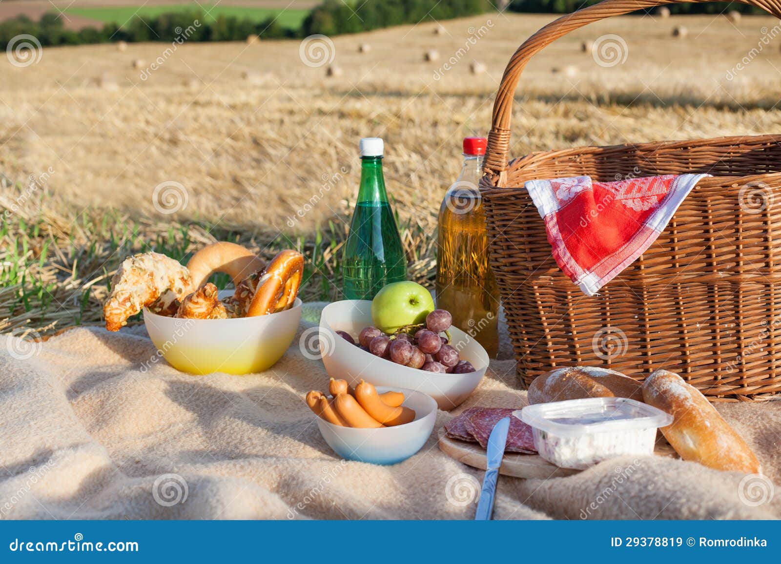 Picnic Basket and Different Food and Drinks on Straw Field Stock Image