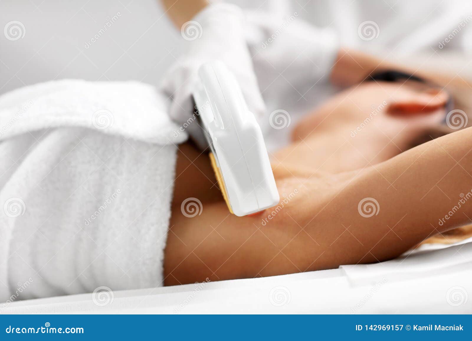 beautician giving epilation laser treatment to woman on armpits