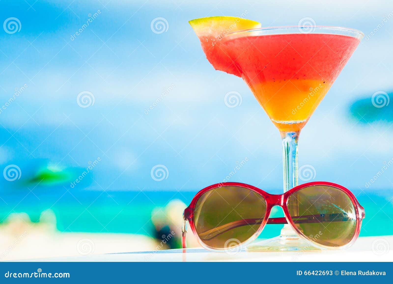 Picture of fresh red and yellow cocktail with sunglasses near tropical. Remote tropical beaches and countries. travel concept