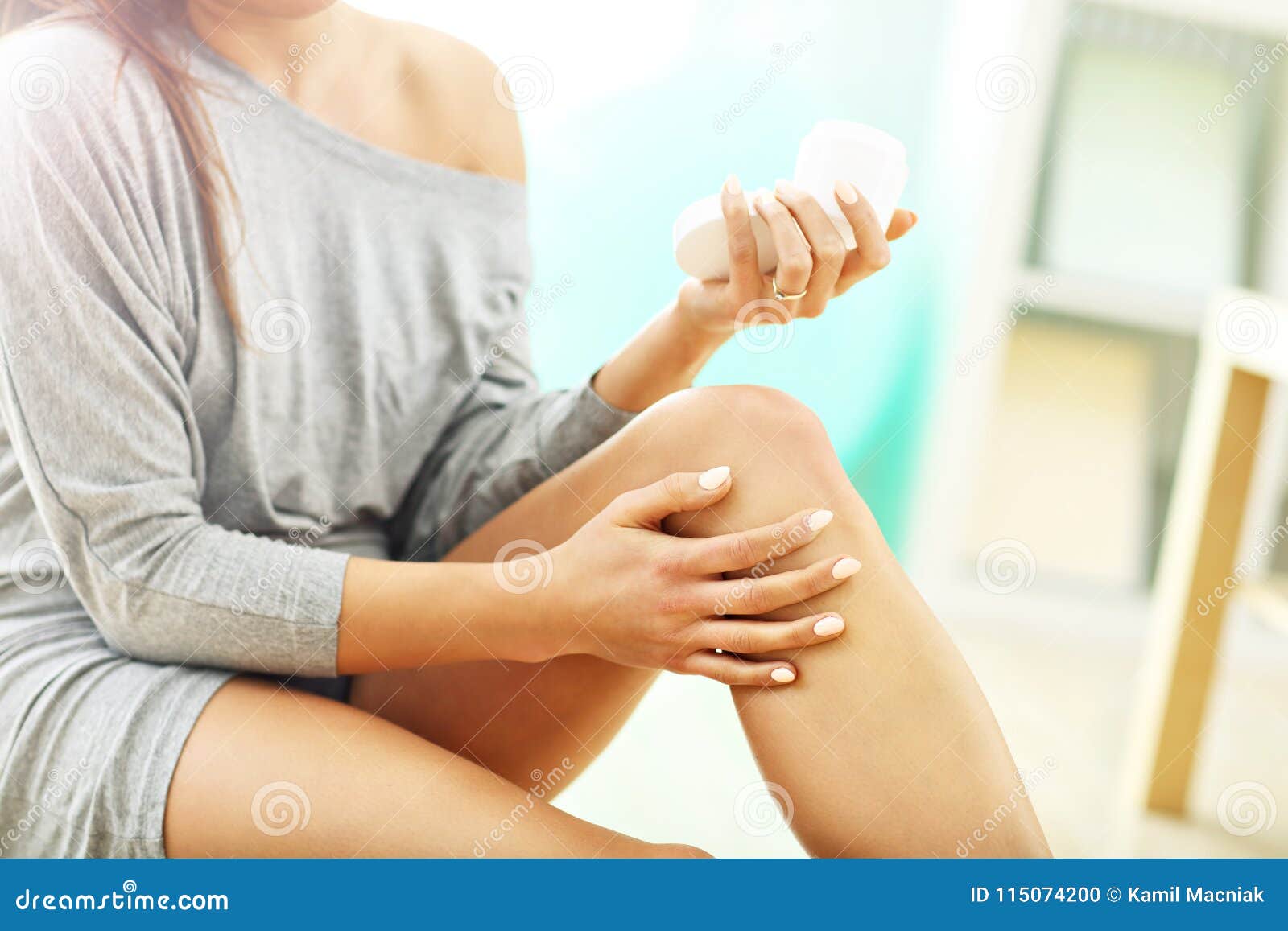 woman using body lotion on her legs