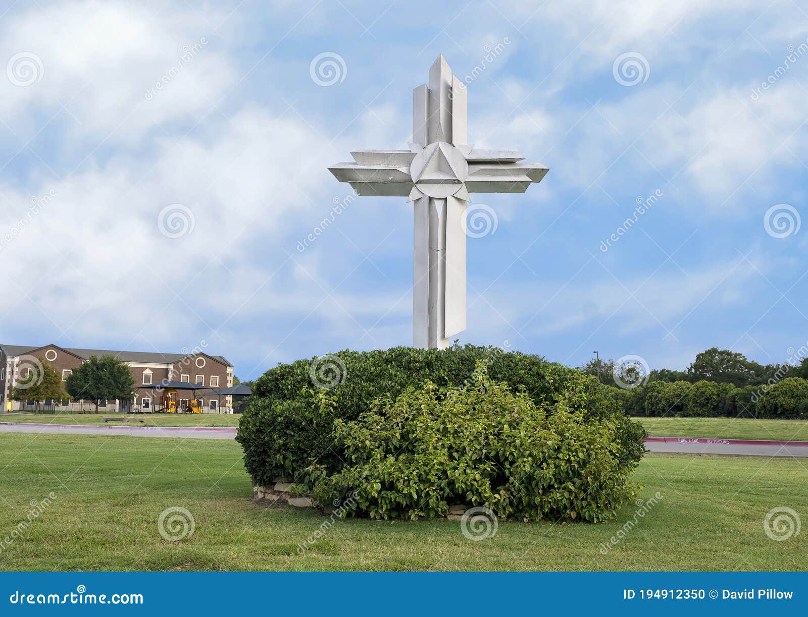 ornate white wooden cross surrounded by green bushes in plano, texas.