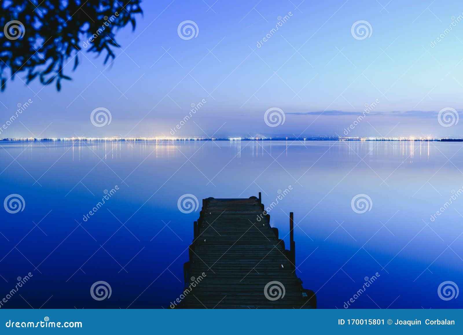 pier on a lake at sunset with calm water and reflections of relaxing lights