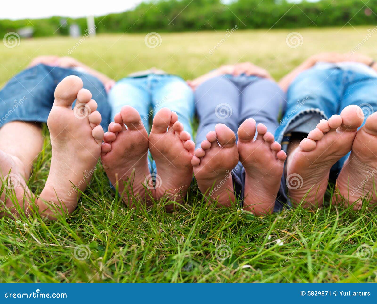 Pies De Adolescentes Que Mienten En Campo Verde Imagen de archivo