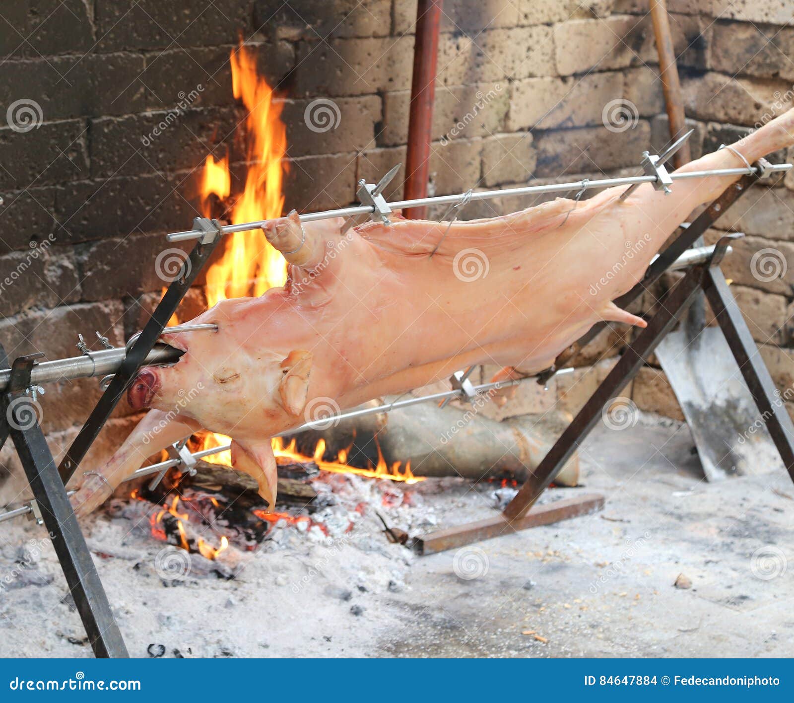 Pig on the Spit and Slowly Cooked on the Large Fireplace Stock Photo