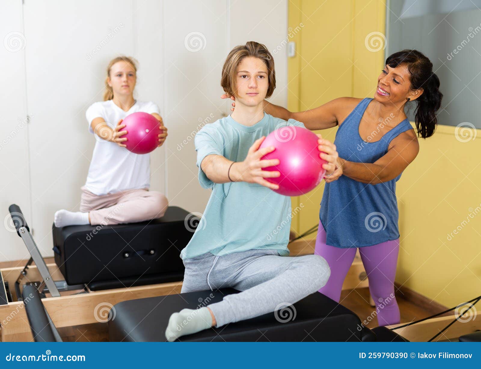 Pilates Instructor Shows Boy How To Exercise With Ball Stock Photo pilates-instructor-shows-boy-how-to-exercise-with-ball-stock-photo